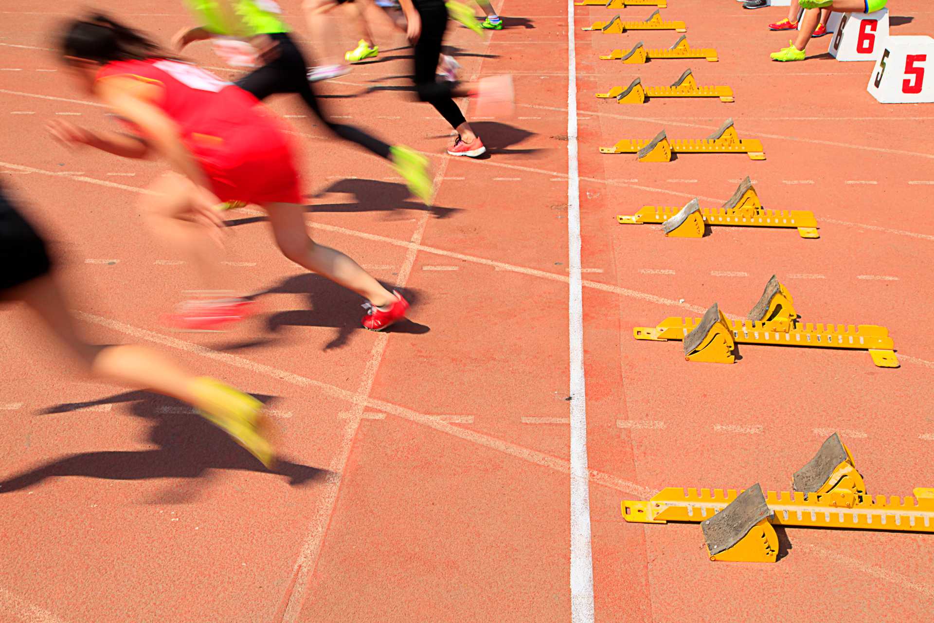 Runners sprinting from starting blocks on an athletics track