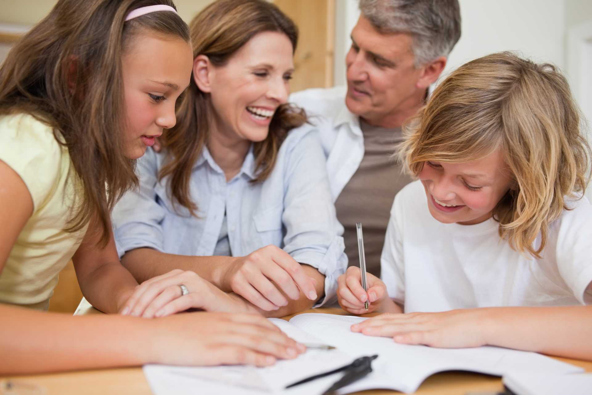 Parents helping children with homework at table